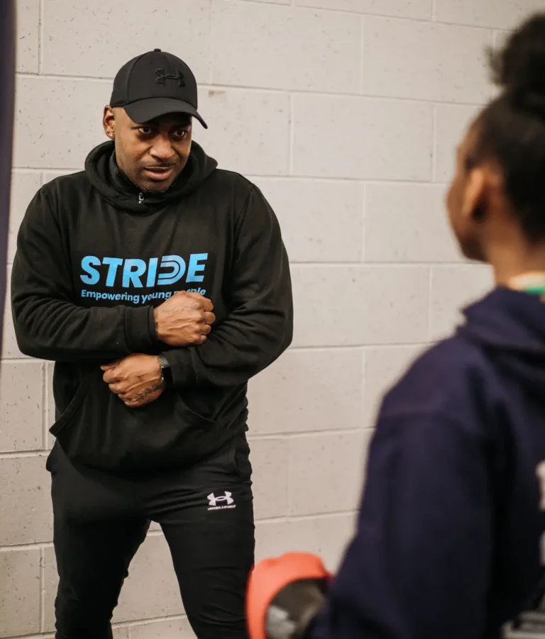 A Stride UK mentor in a branded hoodie talking one to one with a young person